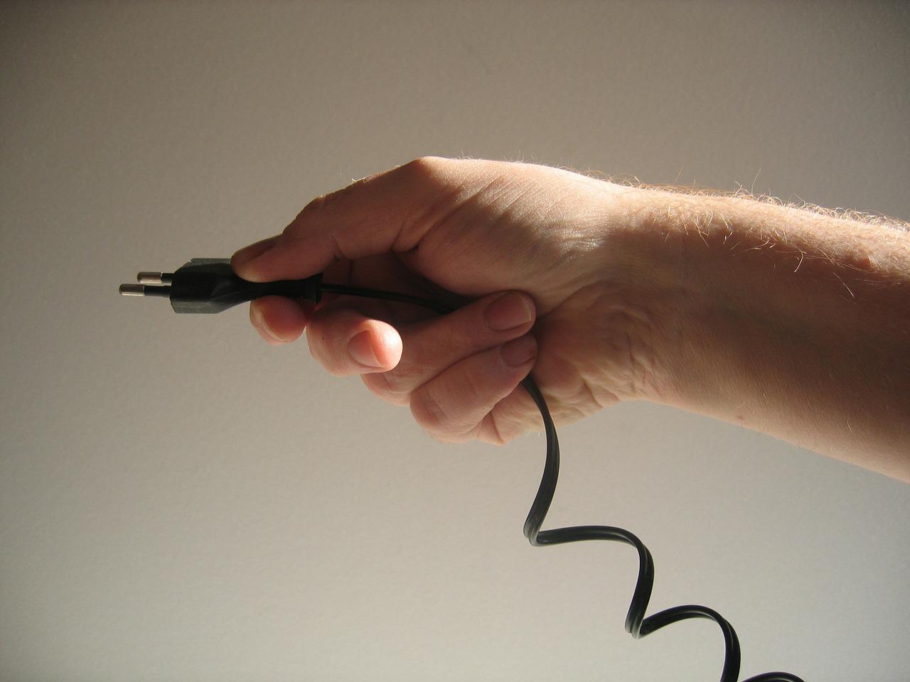 wtyczka z przewodem elektrycznym w dłoni